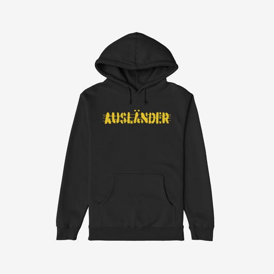 Ausländer Hoodie featuring “AUSLÄNDER” in yellow with a strikethrough, embodies power and resilience. The black pullover design includes a kangaroo pocket, emphasizing individuality and strength against prejudice.