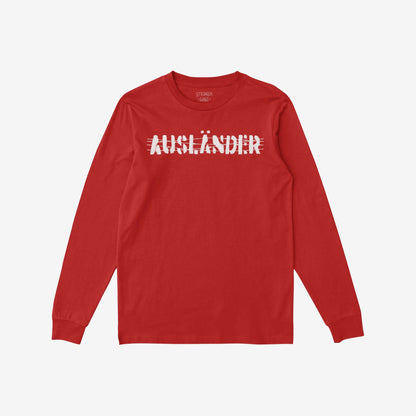Red long-sleeved Ausländer T-shirt with white, distressed strikethrough lettering across the chest; embodies defiance and solidarity against borders, representing resistance and voice against discrimination.