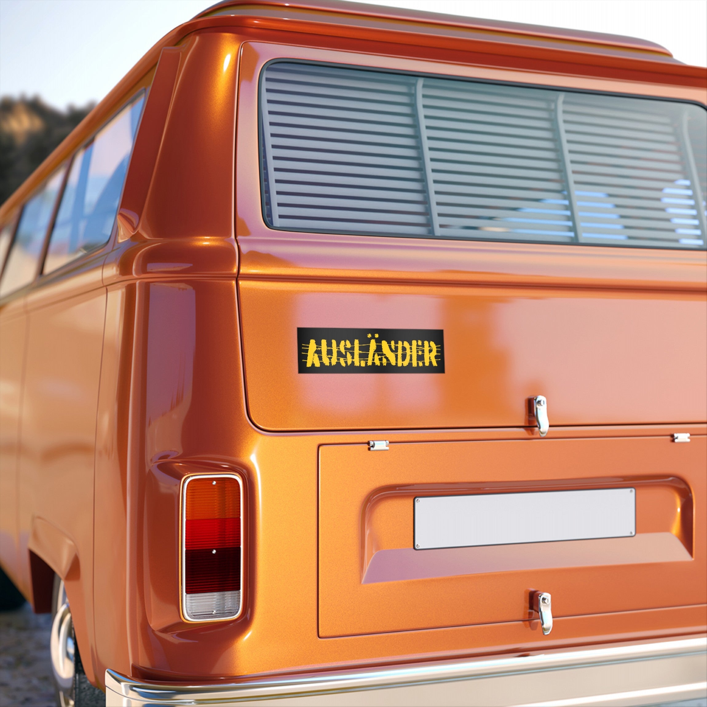 Rear view of a retro orange van featuring an AUSLÄNDIER sticker, symbolizing solidarity with immigrants. Ideal for activists, this vinyl sticker/magnet challenges nationalism and embraces identity.