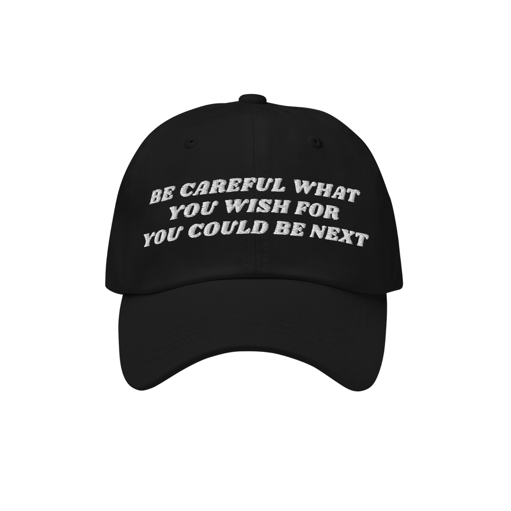 Black Be Careful Hat with white embroidered warning: “BE CAREFUL WHAT YOU WISH FOR YOU COULD BE NEXT”, embodying a bold p