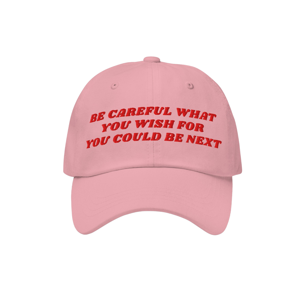The Be Careful Hat features bold red embroidery stating, Be careful what you wish for – you could be next, symbolizing a st