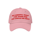 The Be Careful Hat features bold red embroidery stating, Be careful what you wish for – you could be next, symbolizing a st