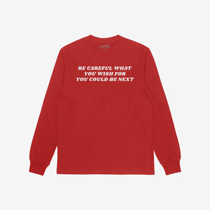 Red long-sleeved Be Careful T-shirt featuring bold white slogan advocating against authoritarianism. The retro typography conveys a rebellious stance, aligning with the ethos of challenging power structures.