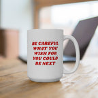 White ceramic Be Careful Mug on a wooden table, featuring bold red text. Ideal for progressives, this mug embodies activism and awareness, aligning with anti-fascist, equality-supporting values. Available in 11 oz and 15 oz sizes.