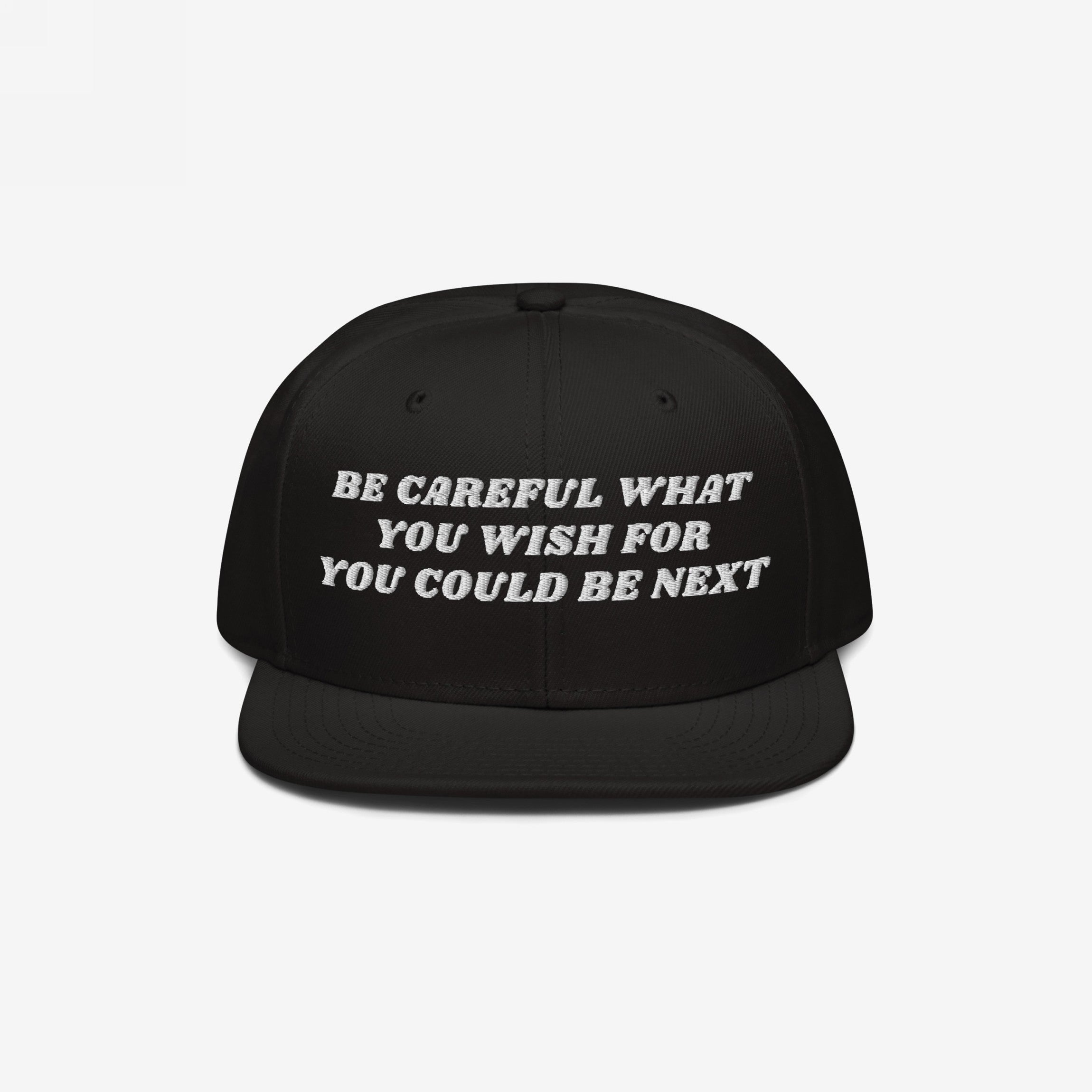 Black flat-brimmed snapback hat with BE CAREFUL WHAT YOU WISH FOR YOU COULD BE NEXT embroidered in white, embodying a bold political statement for justice and activism.