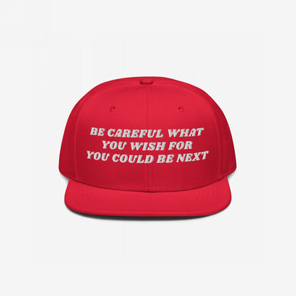 The Be Careful Hat features bold white embroidery with the phrase BE CAREFUL WHAT YOU WISH FOR YOU COULD BE NEXT on a flat-brim snapback, embodying a strong, stylish statement.