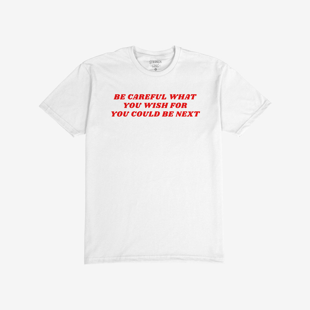 The Be Careful Shirt features bold red text warning against authoritarianism, printed on a white crew-neck T-shirt. Inside the collar, a subtle label reflects its rebellious spirit.