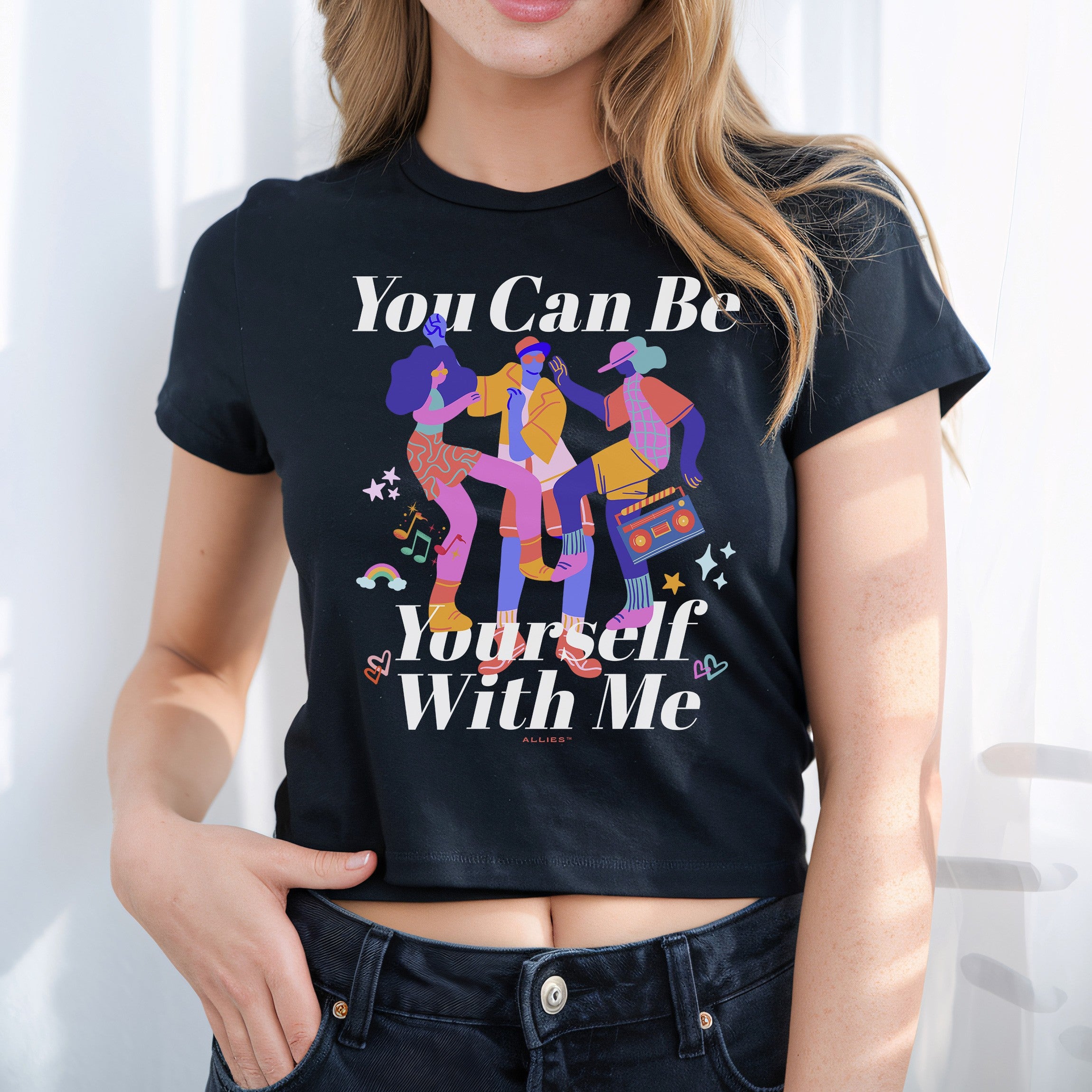 Person wearing the Be Yourself Women's Baby Tee, featuring dancing figures and music doodles with the slogan “You Can Be Yourself With Me,” embodying inclusivity and self-expression.