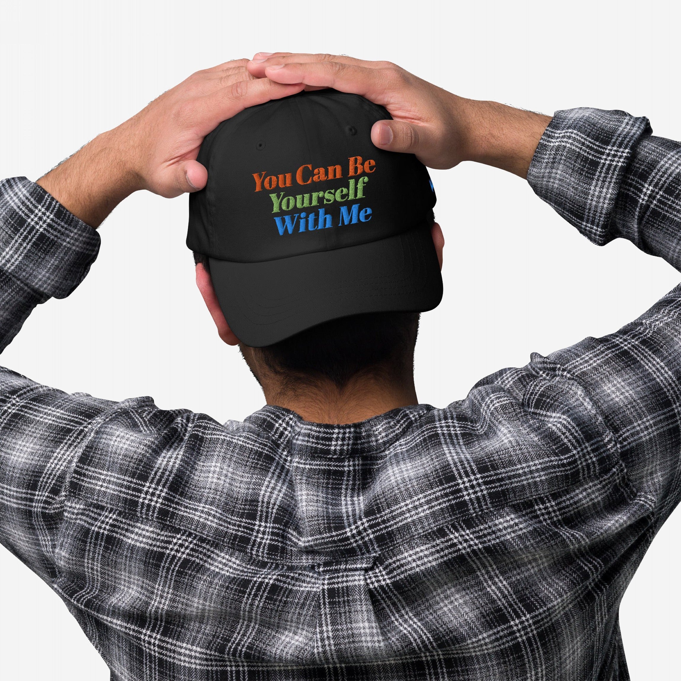 Back view of a person wearing the Be Yourself Hat, featuring the slogan “You Can Be Yourself With Me” in vibrant type, paired with a black-and-white plaid shirt.