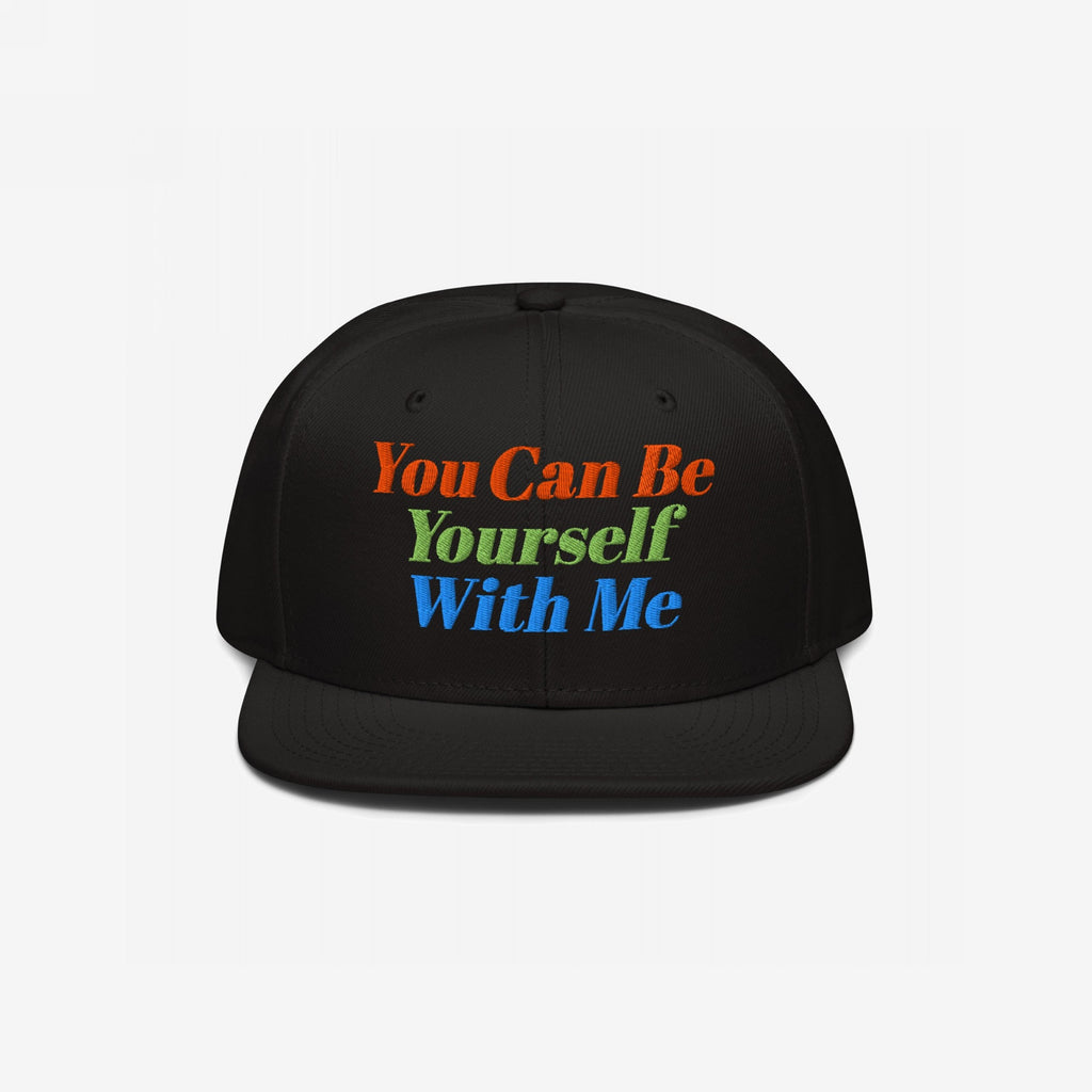 Black flat-brim snapback cap with vibrant embroidered text: You Can Be Yourself With Me. This Be Yourself Hat embodies individuality and inclusivity, reflecting a bold, supportive message.