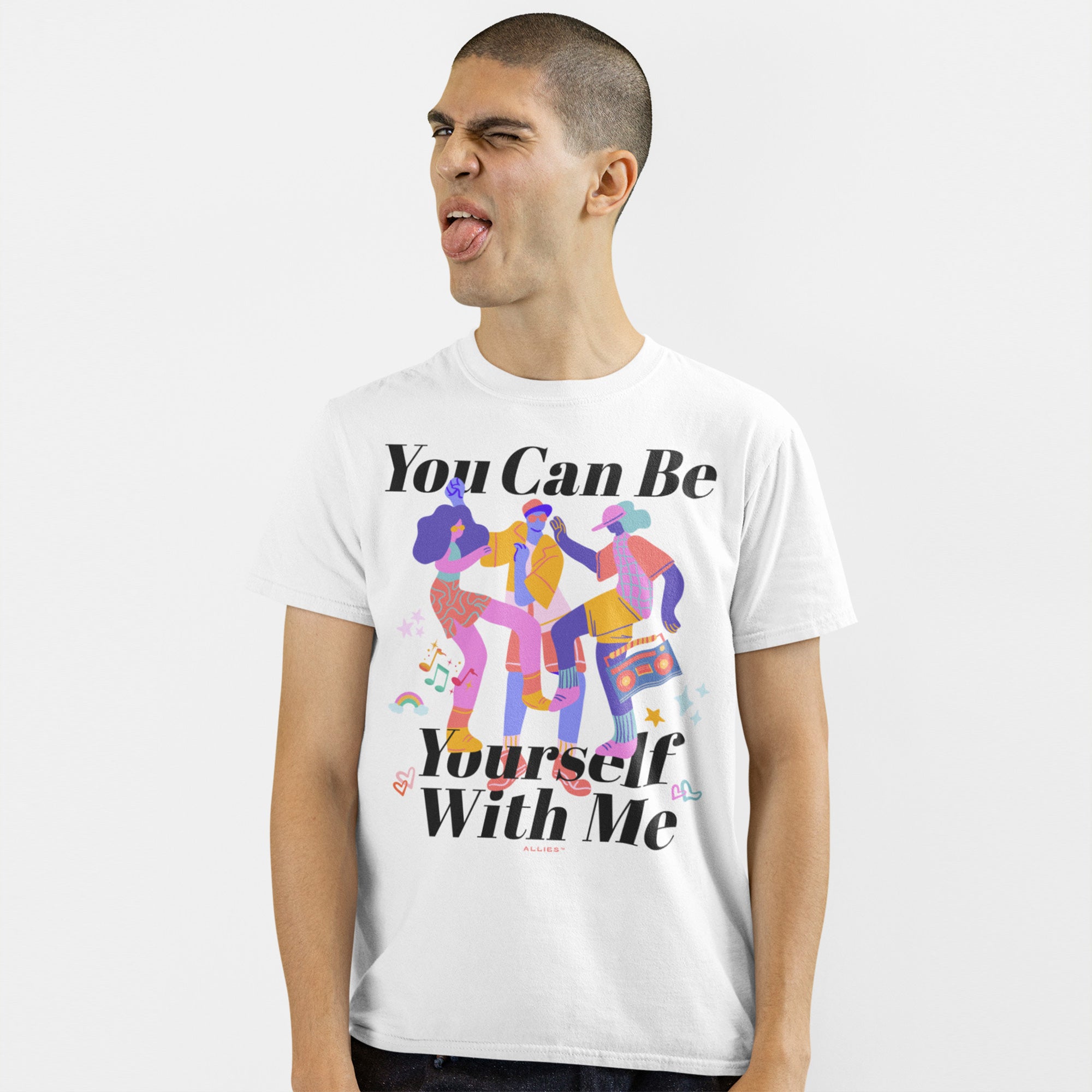 A young man makes a goofy face while wearing the Be Yourself Shirt, featuring playful dancers and text promoting self-expression and inclusivity, supporting The Trevor Project through sales.
