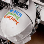 White mesh-back trucker cap under embroidery machine, stitching the phrase “You Can Be Yourself With Me” in vibrant colors on the front, embodying individuality and inclusivity. The Be Yourself Hat.