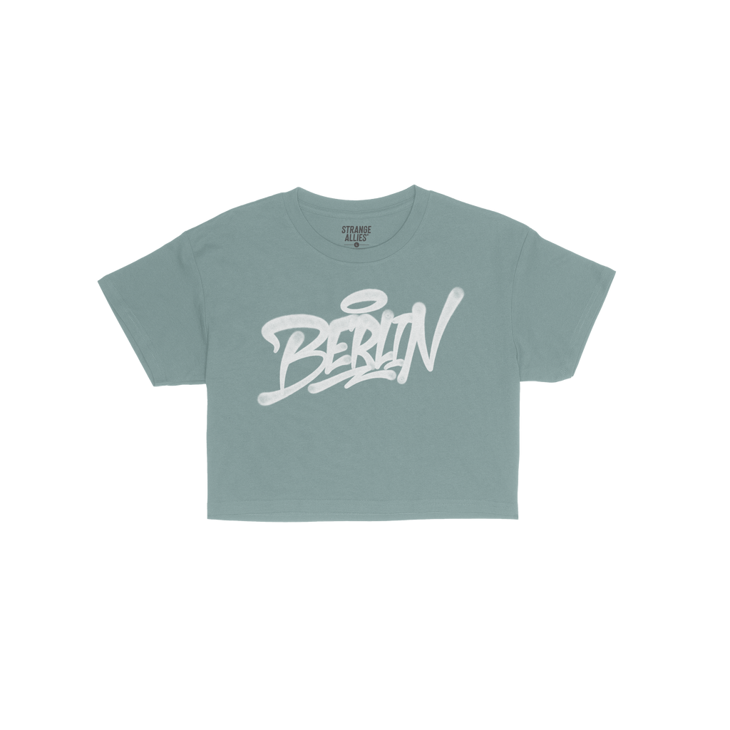 Berlin Handstyle Women's Baby Tee featuring a graffiti-style Berlin graphic on a short-sleeve blue shirt. The design exudes s