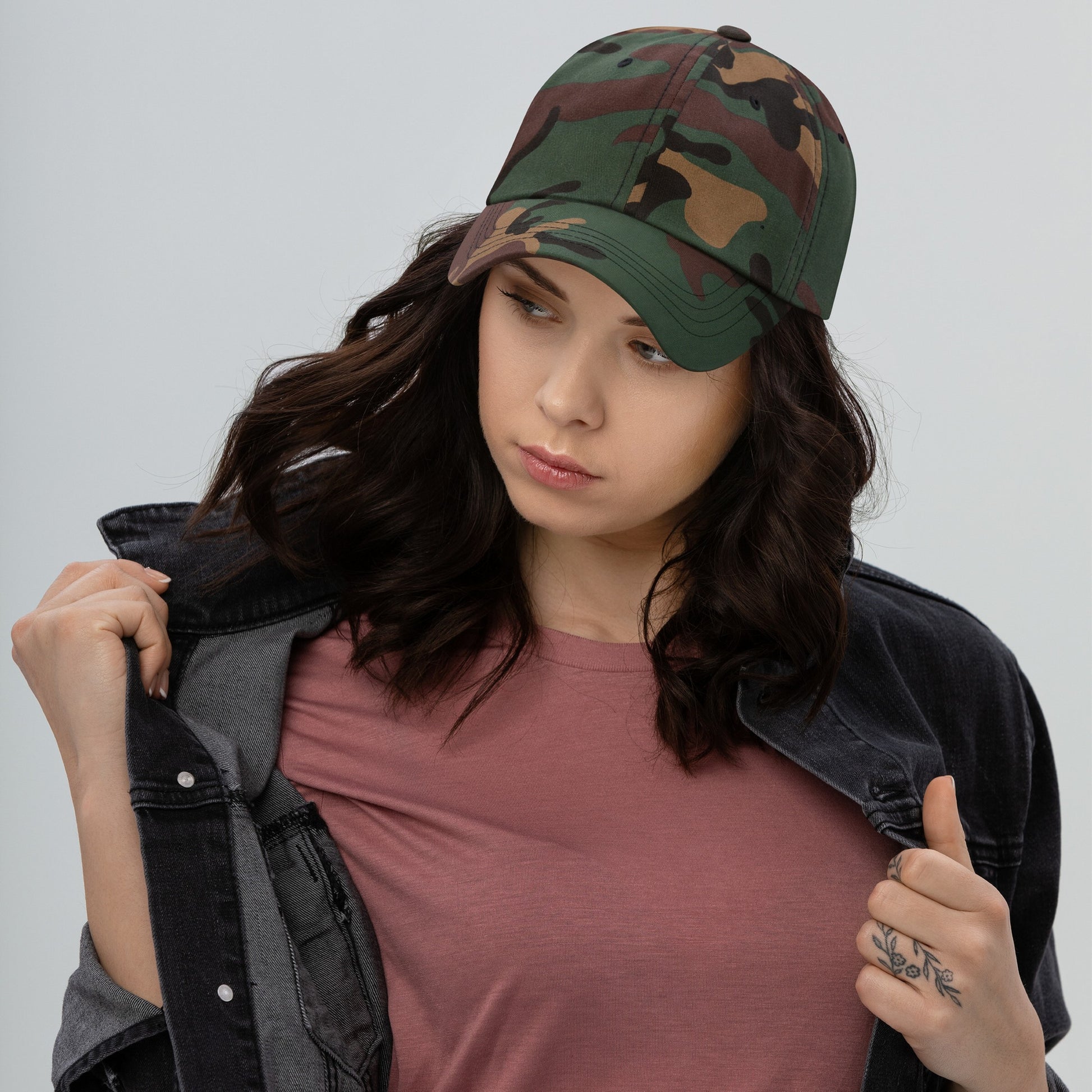 Young woman models a muted rose-pink T-shirt with a dark denim jacket, showcasing the Dad Hat In Custom Colors with an embroidered anti-fascist design, blending activism with casual style.