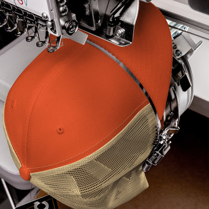 A Trucker Hat In Custom Colors being embroidered on a commercial machine with a hat clamp, capturing the bold design and structured, breathable construction suited for activism or casual wear.