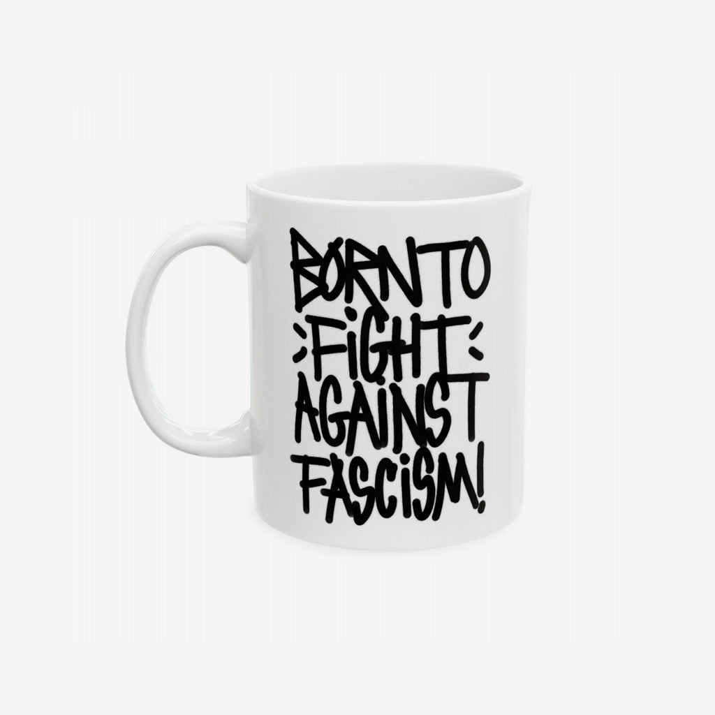 Born To Fight Against Fascism Graffiti Mug featuring a bold black graffiti-style slogan on a white ceramic surface, emphasizing resistance and activism. Handle visible on the left against a light backdrop.