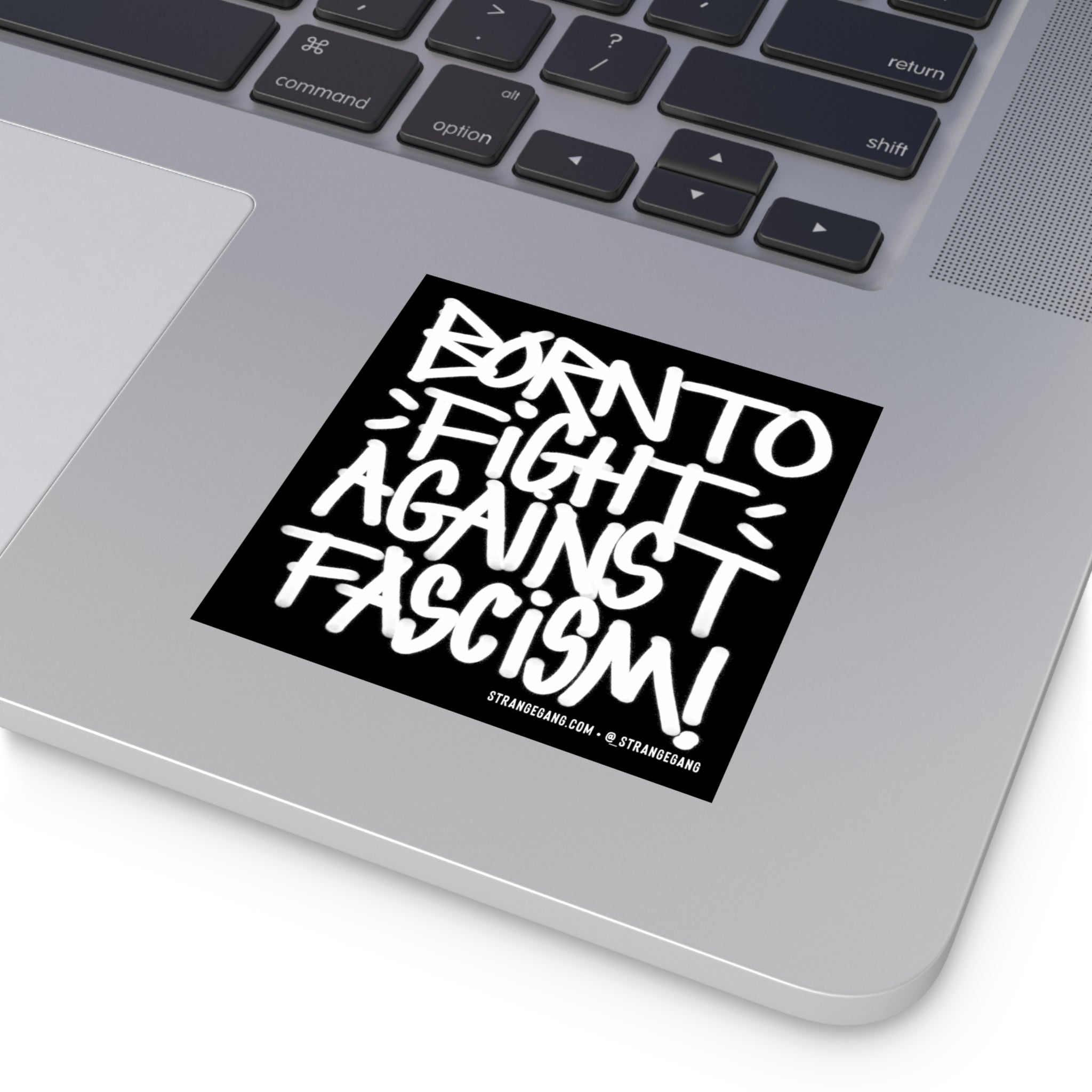 “Born To Fight Against Fascism Graffiti Sticker & Magnet” displayed on a silver laptop's palm rest, showcasing bold hand-drawn text, emphasizing a rebellious, anti-fascist message, ideal for expressing progressive beliefs.