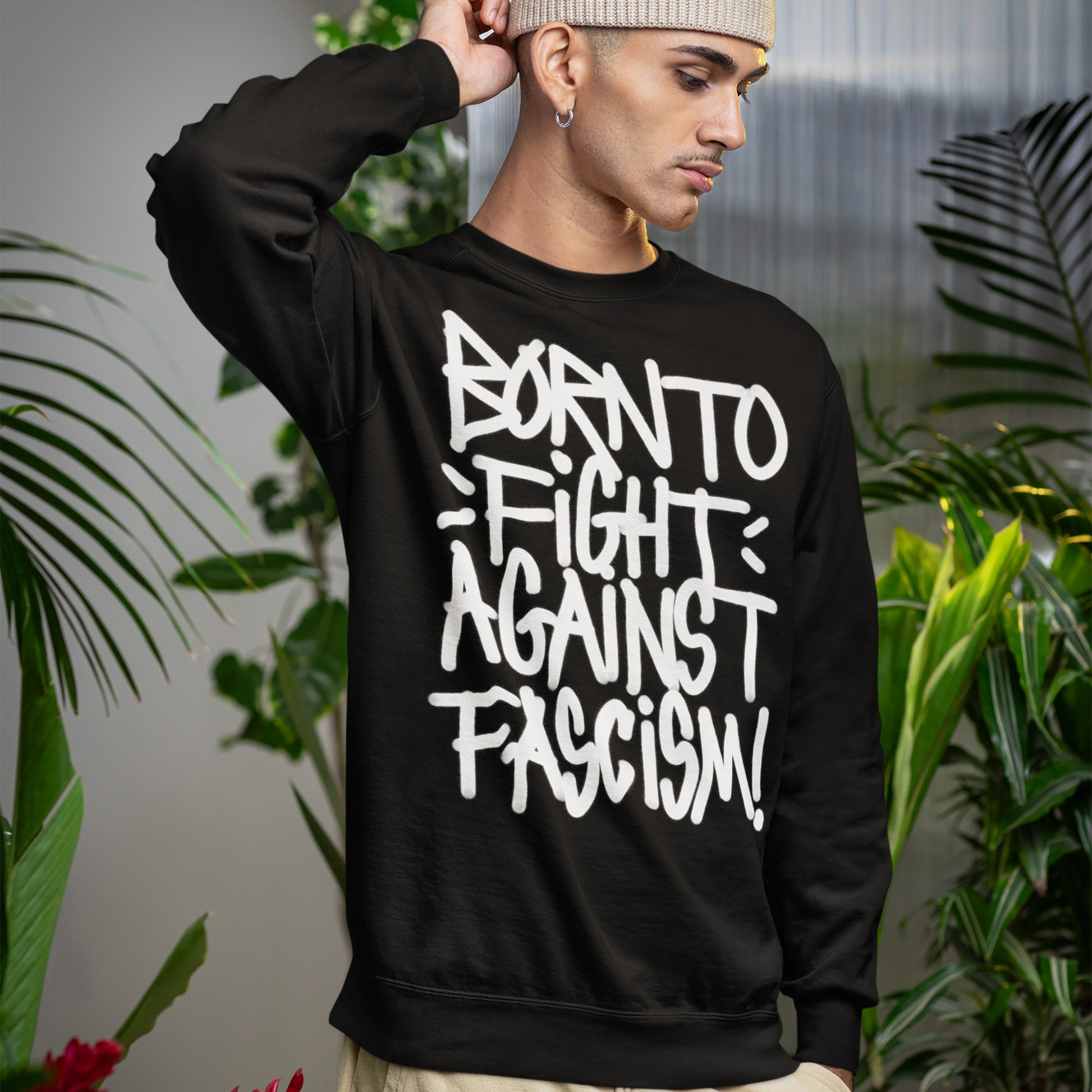 Young person in a black sweatshirt with bold white graffiti reading “Born To Fight Against Fascism Graffiti Shirt,” embodying rebellious spirit and resistance against tyranny; proceeds support the ACLU.