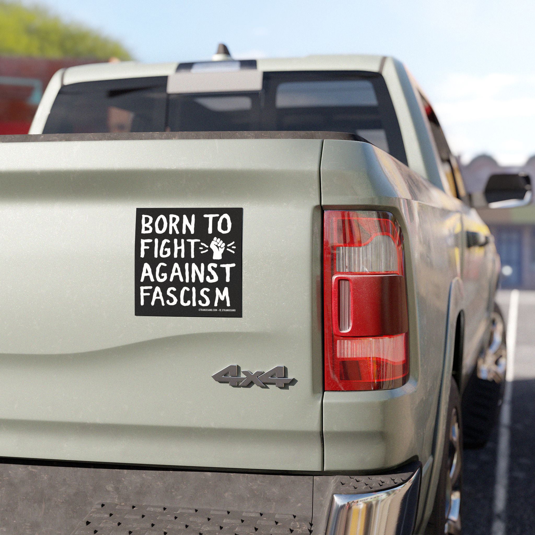 The tailgate of a 4×4 pickup displays a Born To Fight Against Fascism decal with a raised-fist graphic, symbolizing resistance, reflecting the product's bold stance against tyranny and injustice.
