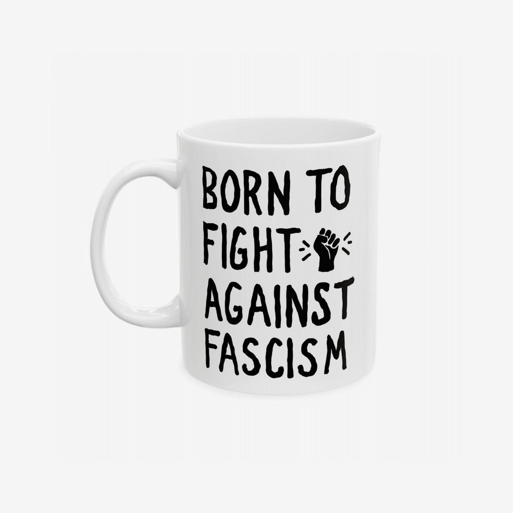 White ceramic mug with bold black slogan BORN TO FIGHT AGAINST FASCISM and a stylized raised-fist graphic, emphasizing progressive resistance. Available in 11 oz. and 15 oz., supporting ACLU.