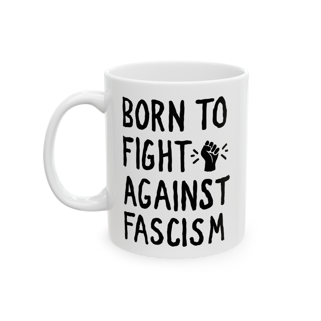 White ceramic mug with bold black slogan BORN TO FIGHT AGAINST FASCISM and a stylized raised-fist graphic, emphasizing progre