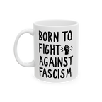 White ceramic mug with bold black slogan BORN TO FIGHT AGAINST FASCISM and a stylized raised-fist graphic, emphasizing progre