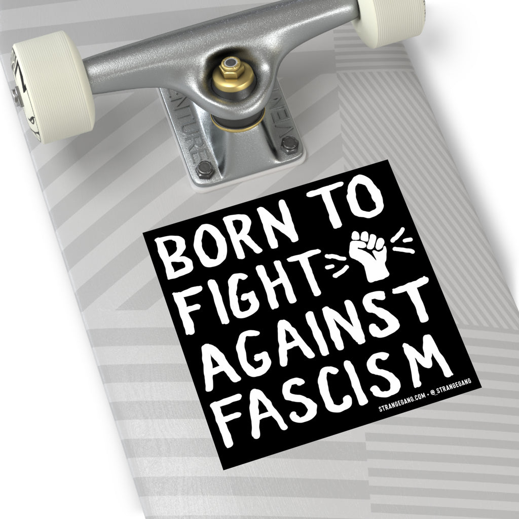 The underside of a skateboard features the Born To Fight Against Fascism sticker with hand-drawn lettering and a raised fist, symbolizing resistance and equality.