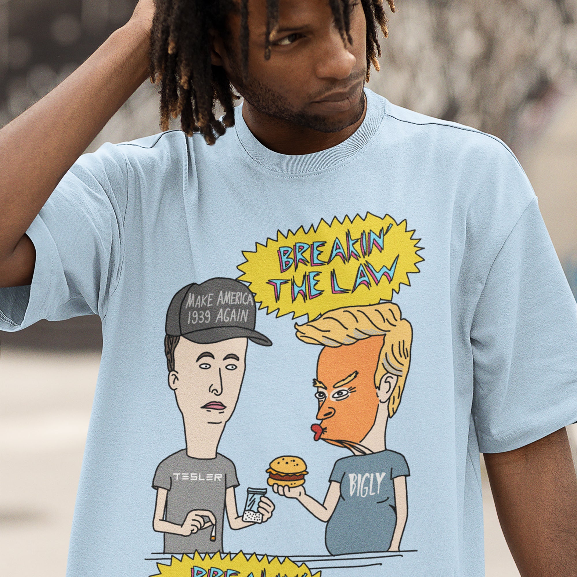 Breakin' The Law Shirt features a satirical cartoon of caricatured figures resembling Trump and Musk, humorously engaging with contraband and fast food, embodying anti-elitist and protest-centric themes.