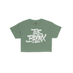 Bronx Handstyle Women's Baby Tee features “THE BRONX” in bold, graffiti-style script on a green short-sleeve shirt, embod