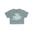 Bronx Handstyle Women's Baby Tee features a navy-blue, short-sleeve design with a white graffiti-style THE BRONX graphic, cap