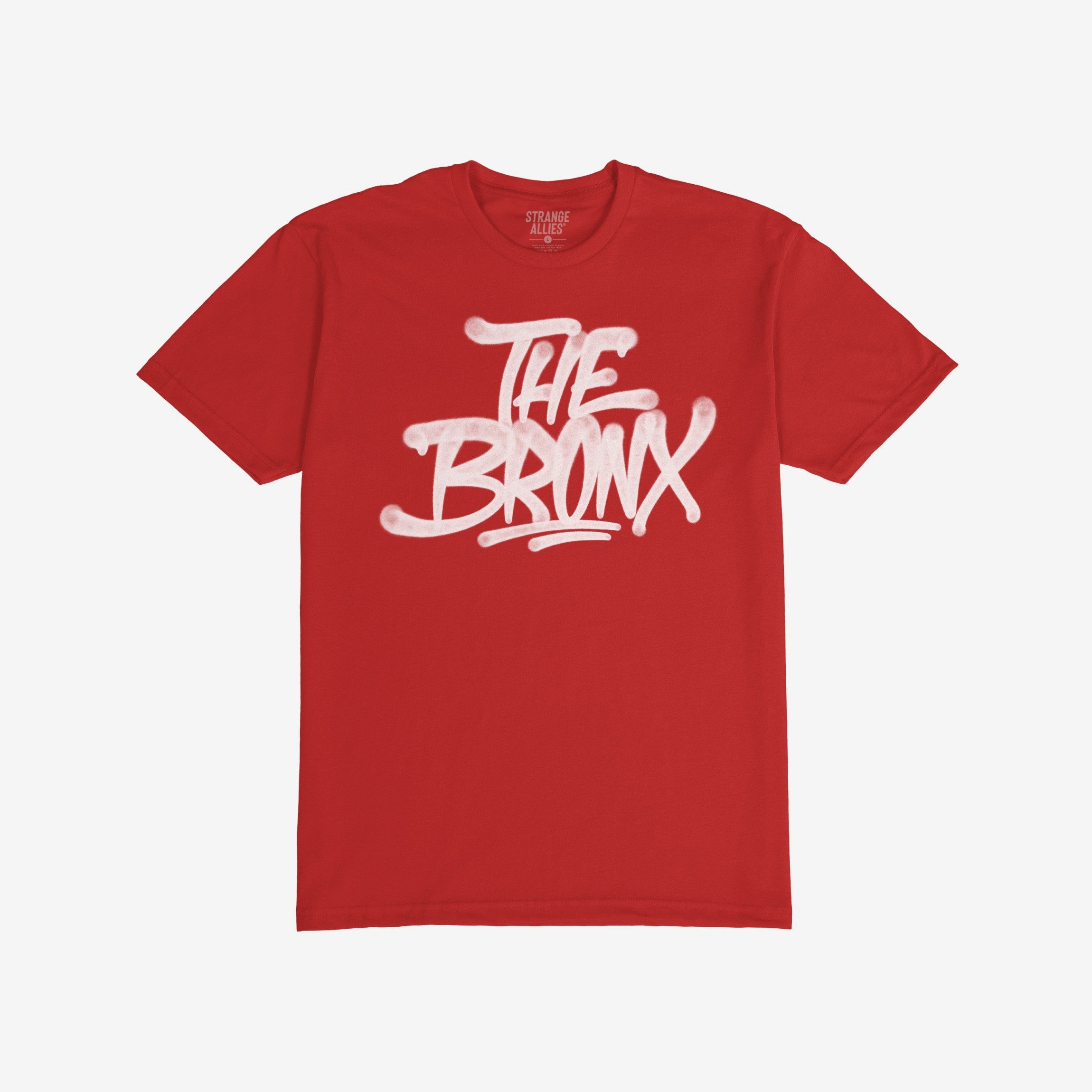 Bronx Handstyle T-shirt features bold “THE BRONX” graffiti in white spray-paint lettering on a red tee, capturing raw borough pride and urban spirit. Brand “STRANGE ALLIES” visible inside the collar.