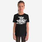 Child wearing Bronx Handstyle T-shirt with bold, white graffiti-style THE BRONX logo, embodying urban pride and rebellious spirit. Hair in braids, neutral expression, light background. Perfect for NYC enthusiasts.