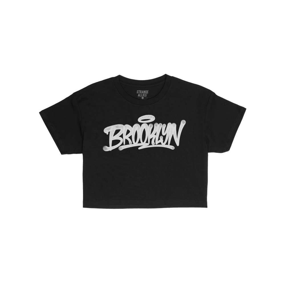 Brooklyn Handstyle Women's Baby Tee features a black design with white graffiti-style BROOKLYN lettering and a halo, embodyin