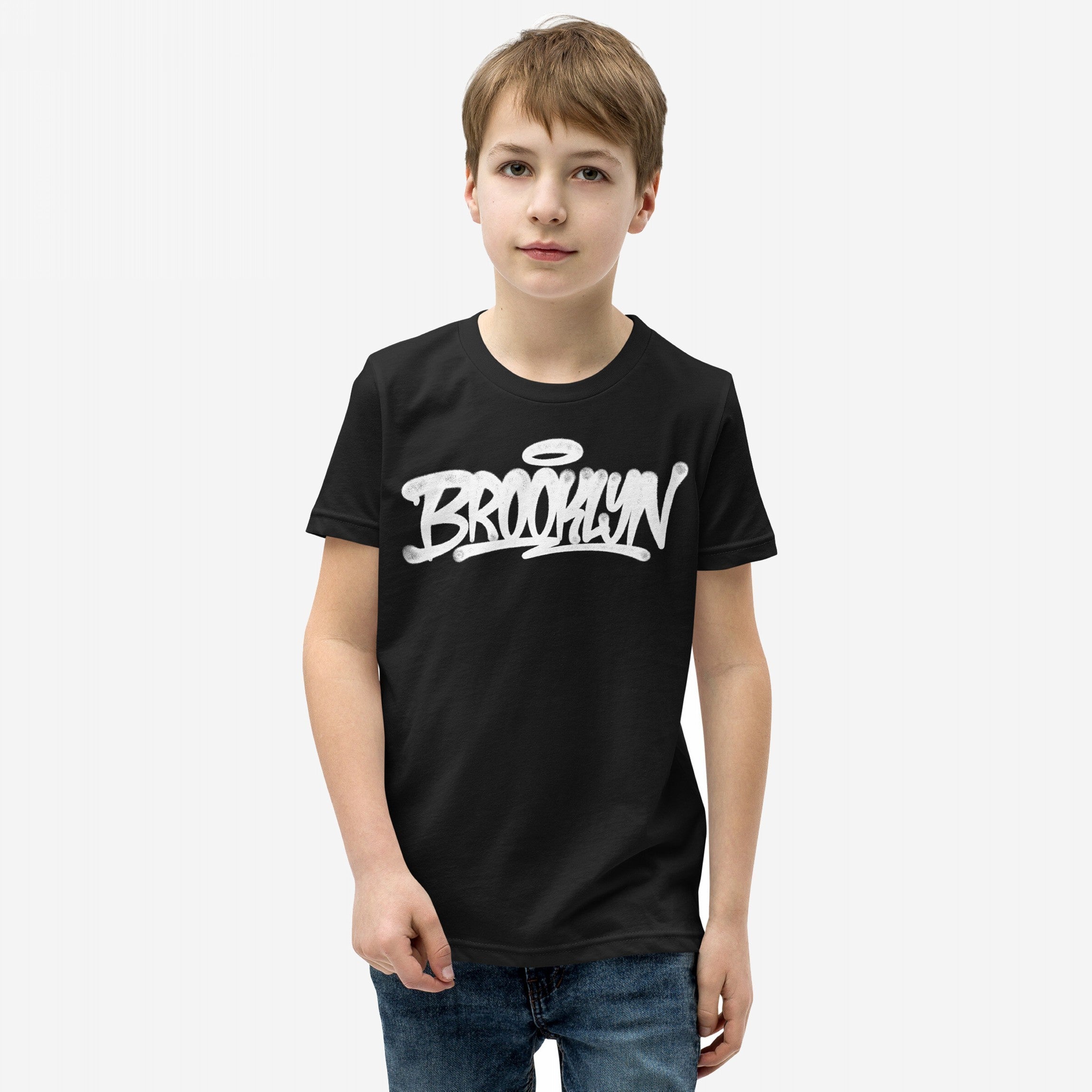 Young boy wearing the Brooklyn Handstyle T-shirt with graffiti-style Brooklyn script and halo accent, embodying everyday borough pride. Suitable for various occasions, from school to city adventures.
