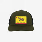 California Gadsden Flag Trucker Hat with an olive front and black mesh back. Features a leatherette patch with a bear and the phrase “DON’T TREAD ON US,” symbolizing defiance and unity.