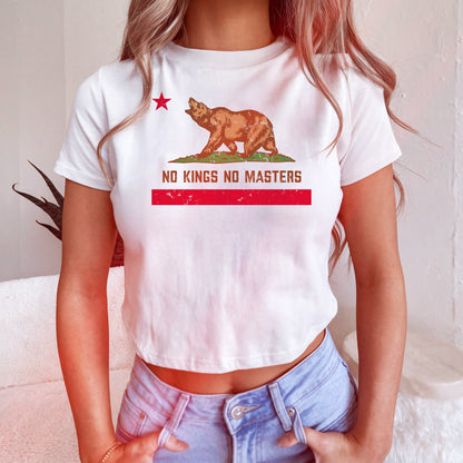 California No Kings Flag Women's Baby Tee features a bold bear and anti-authoritarian message, combining retro style with a rebellious twist, paired with light-wash jeans for a spirited look.