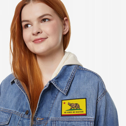 A young person wears a blue denim jacket with the California Flag No Kings Patch, featuring a bear on yellow, symbolizing rebellion against hierarchy.