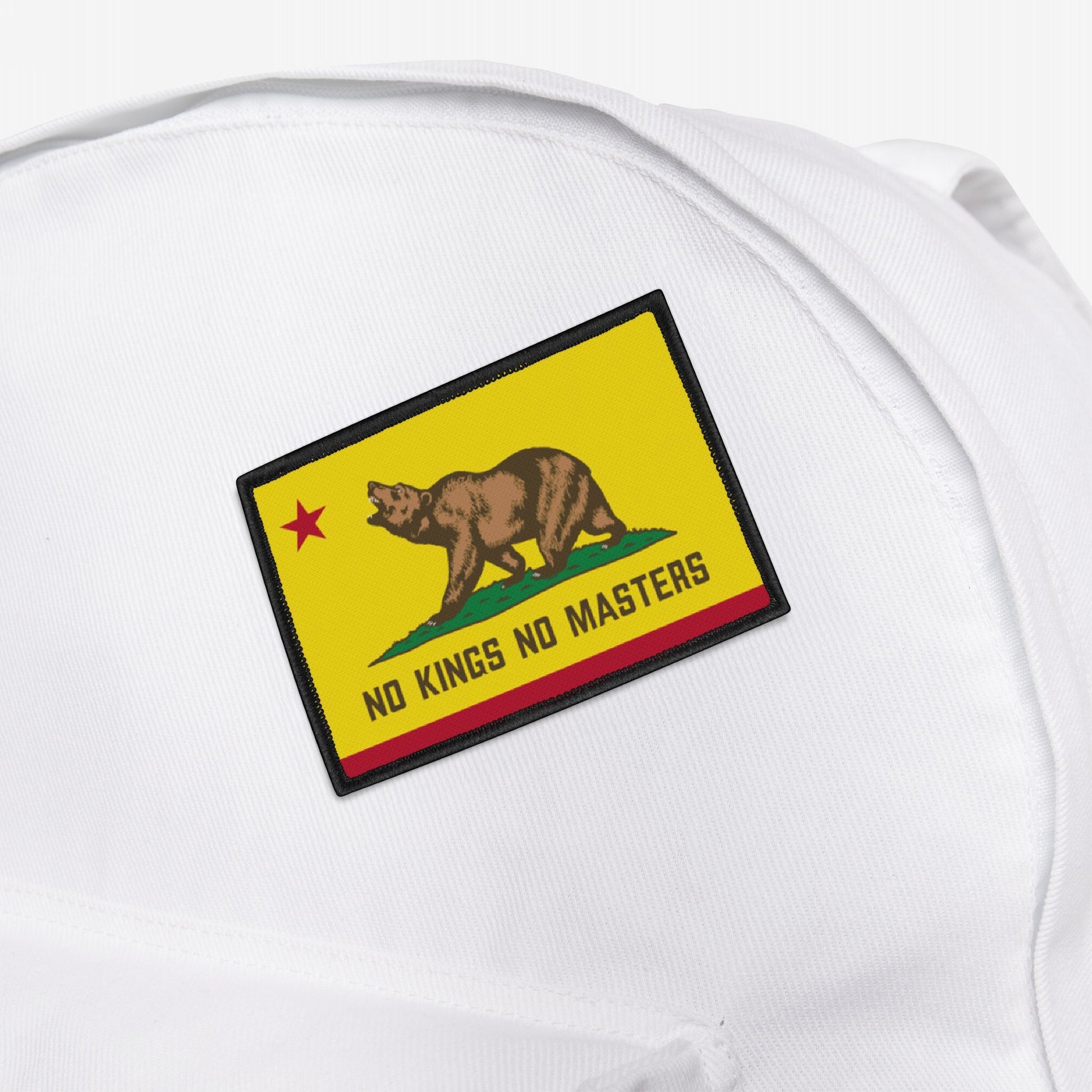 The California Flag No Kings Patch features a grizzly on grass with a red star, subtly styled with NO KINGS NO MASTERS text, symbolizing rebellion. Perfect for personalizing backpacks or apparel.