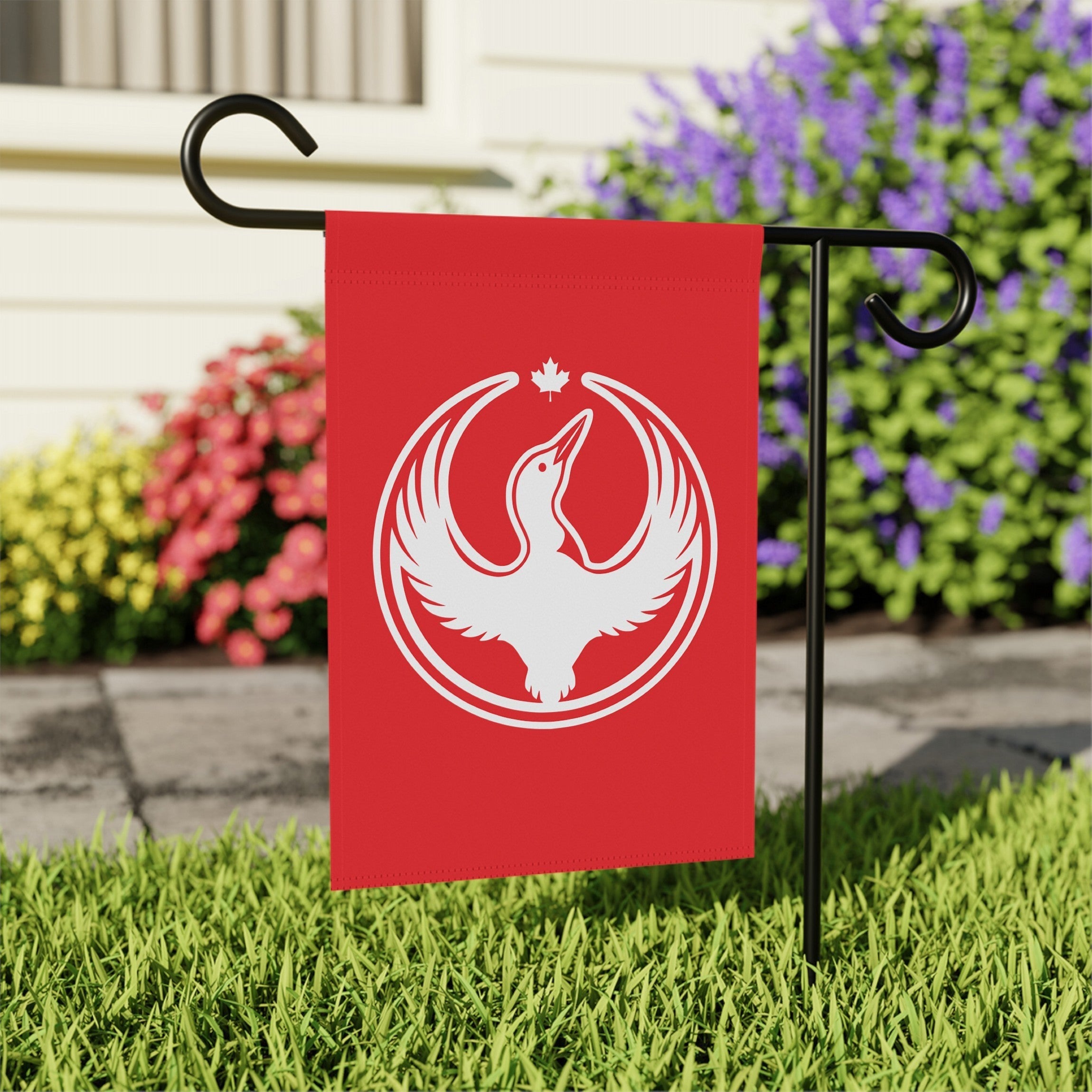 Canada Rebel Alliance Garden Flag featuring a white loon emblem with a maple leaf, mounted on a black stand, displayed in a lawn setting. Perfect for anti-fascist, pro-equality expressions in outdoor spaces.