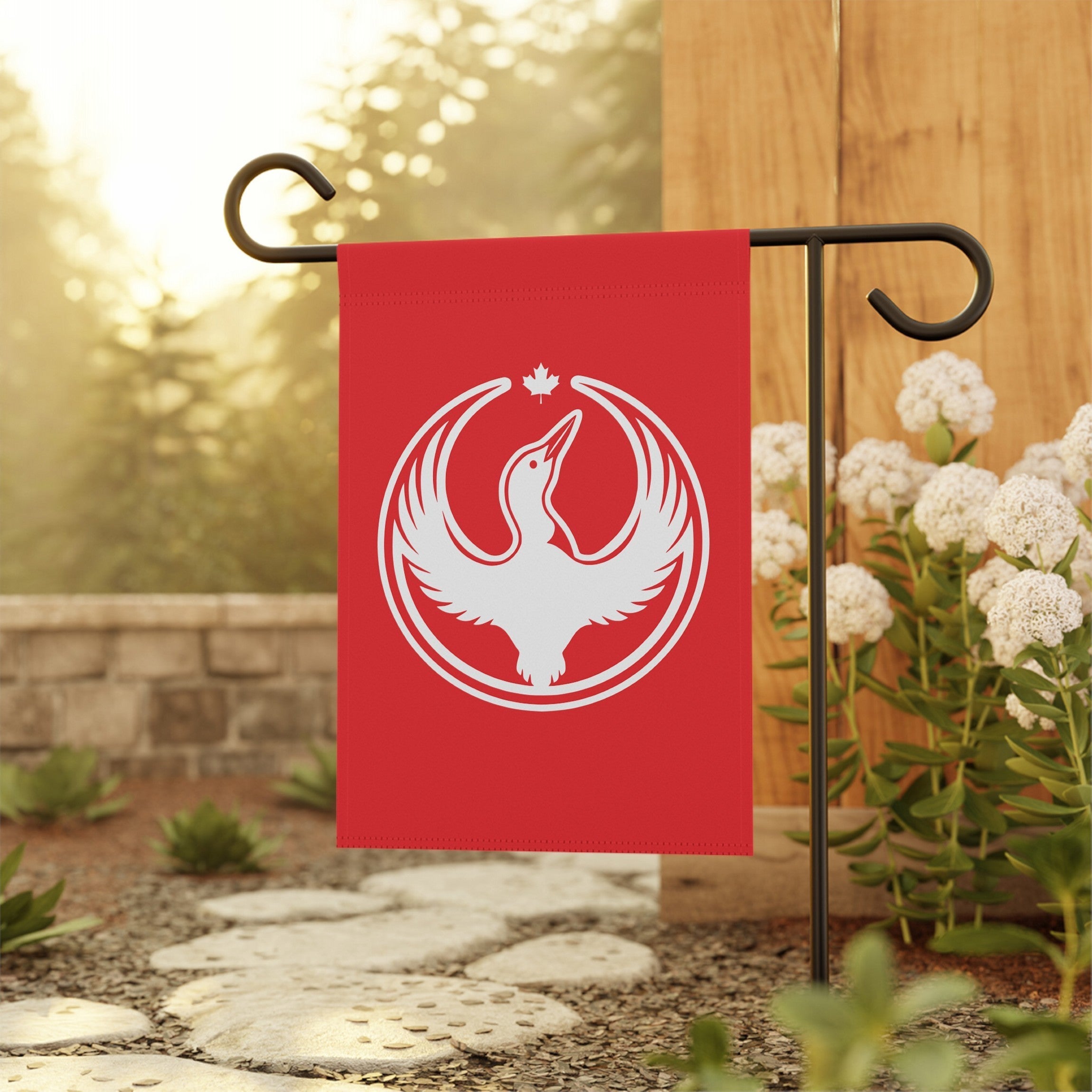 Canada Rebel Alliance Garden Flag on a black metal stand in a yard, featuring a white goose with wings spread, a maple leaf icon above, representing anti-fascism and community defense.