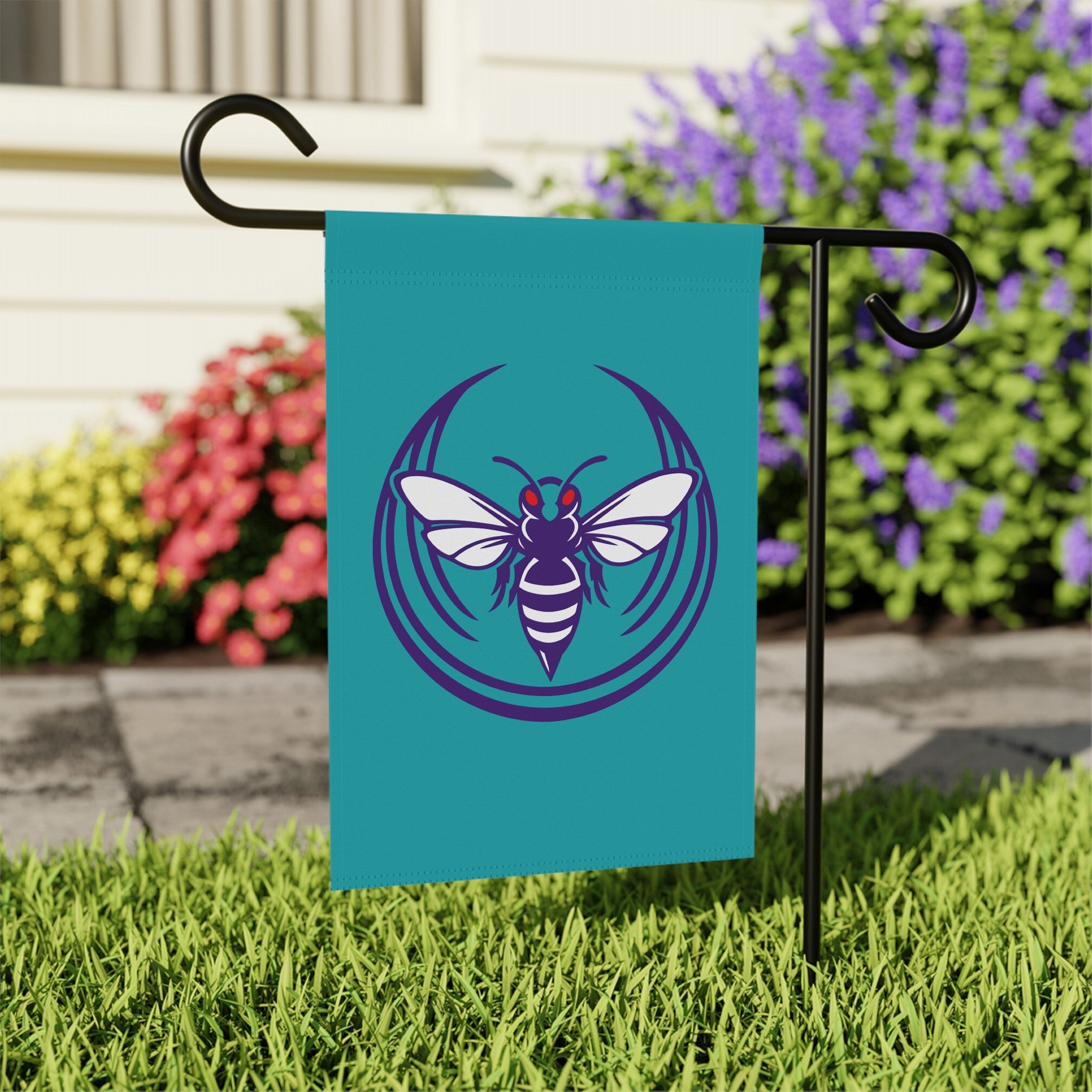 Charlotte Rebel Alliance Garden Flag displayed on a black metal stake in a garden, featuring a stylized insect emblem. Perfect for supporting anti-fascist and immigrant rights, printed on durable poly poplin-canvas fabric.