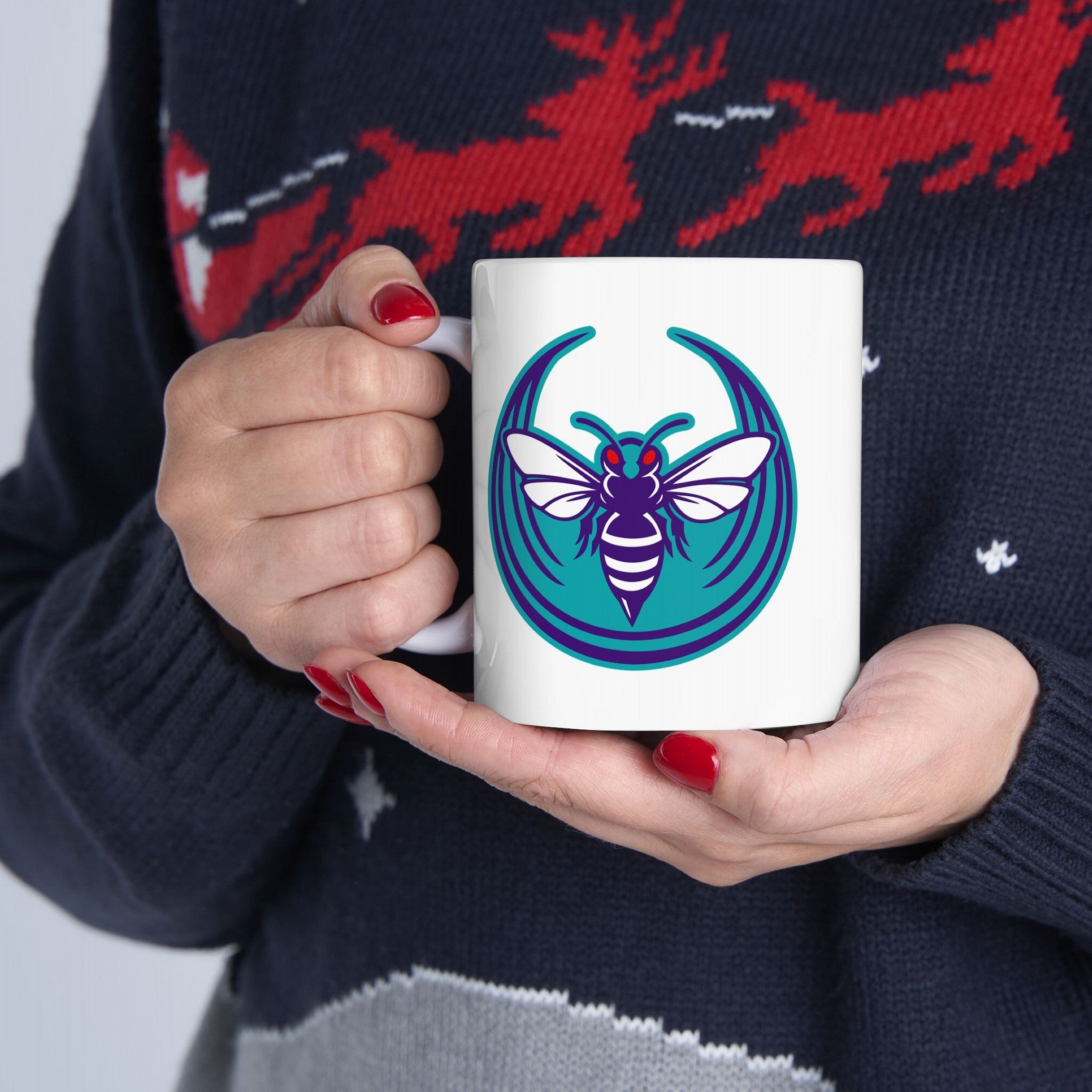 Person holding a Charlotte Rebel Alliance Mug featuring a teal, purple, and white hornet logo with red eyes. The mug represents Charlotte's anti-fascist and pro-equality stance, available in 11 oz. and 15 oz. sizes.