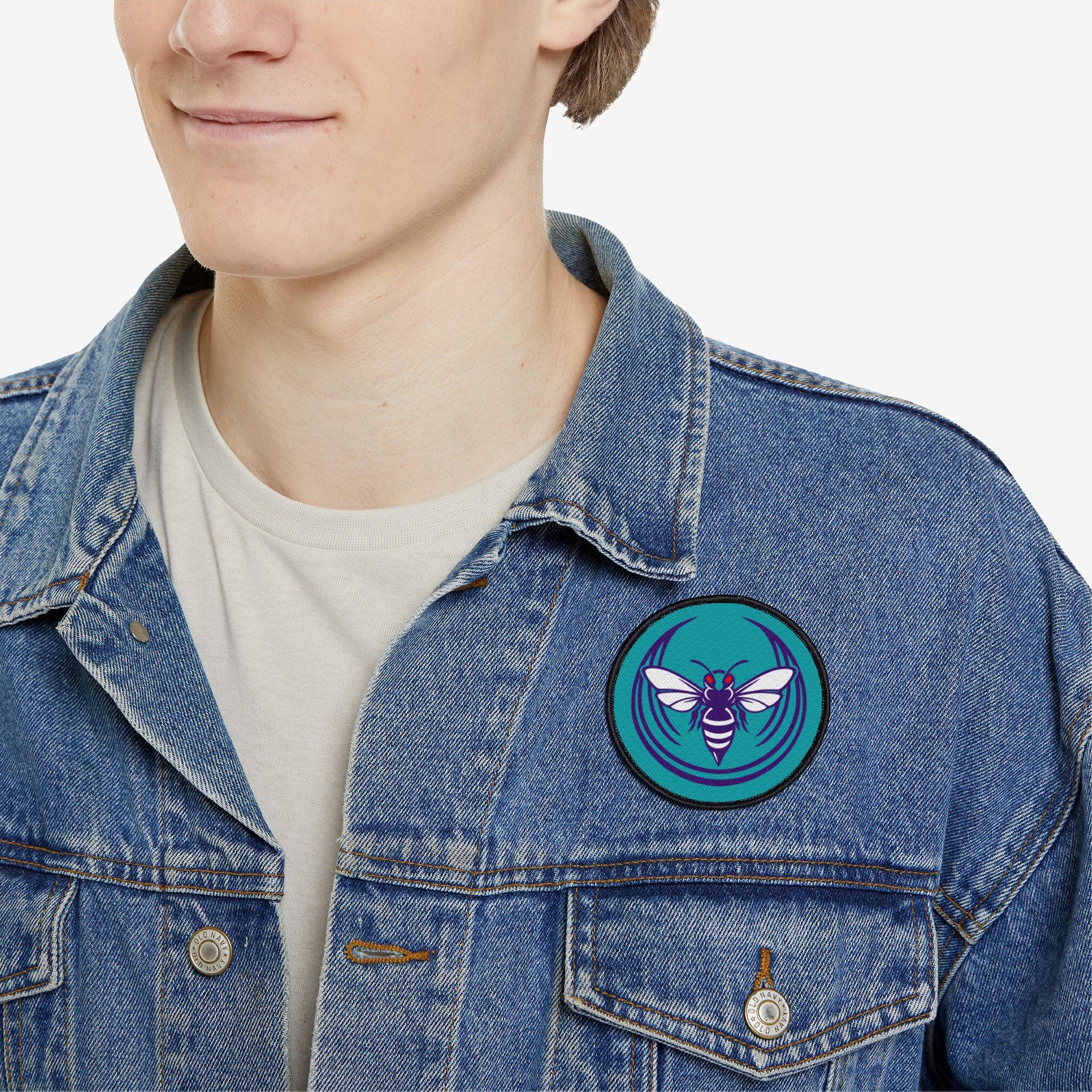Charlotte Rebel Alliance Patch on a light-wash denim jacket, showcasing a stylized hornet design. The patch, 3x3, symbolizes anti-fascist support and Charlotte pride with its striking teal and purple accents.