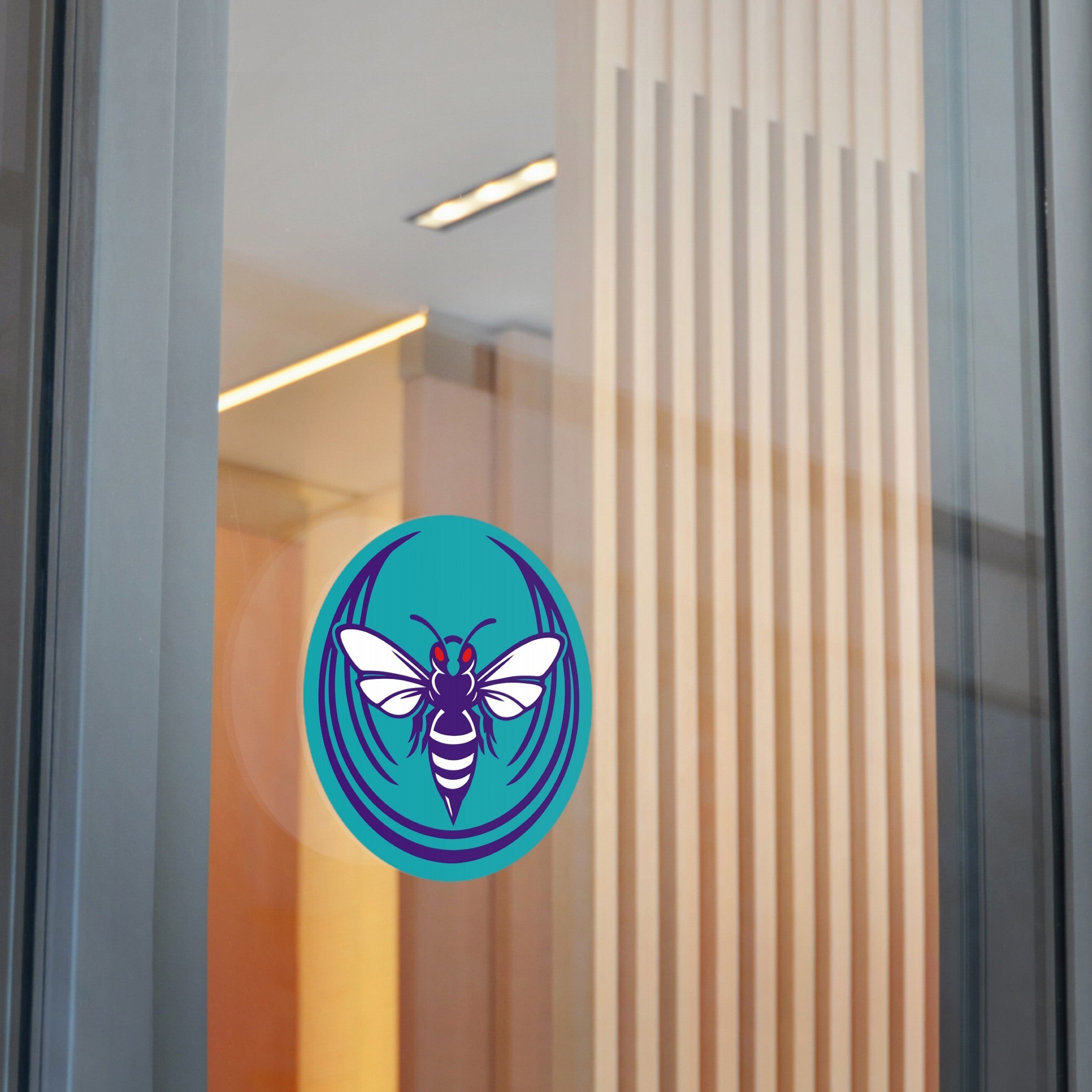 Charlotte Rebel Alliance Sticker on glass pane, showing a stylized wasp with red eyes and white wings. This vinyl decal promotes anti-fascism and equality, available in sizes for laptops and water bottles.