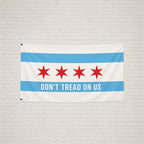 Chicago Gadsden Flag hanging on a light brick wall, featuring Chicago's stars and text DON’T TREAD ON US on a sky-blue stripe, symbolizing protest and resistance.
