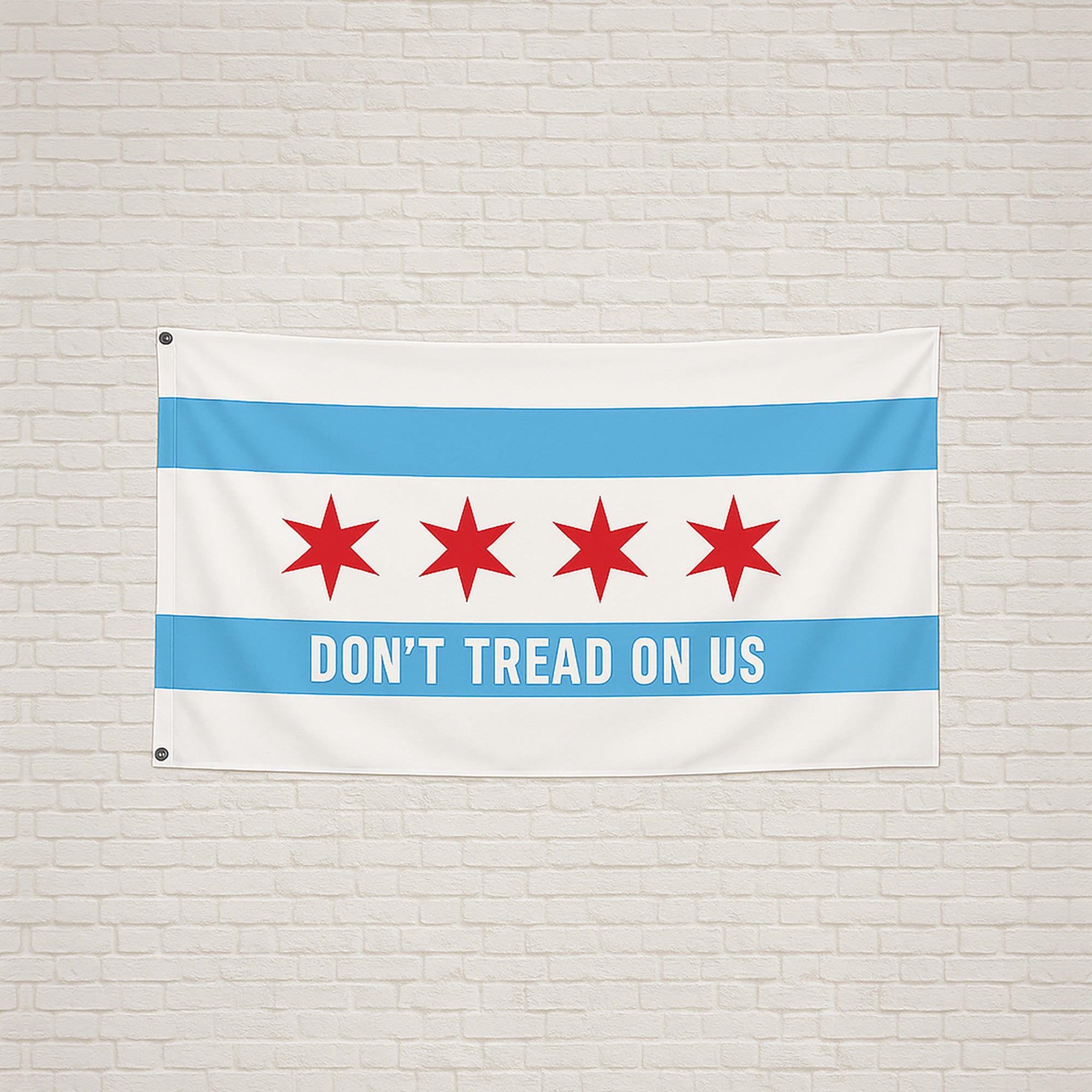 Chicago Gadsden Flag hanging on a light brick wall, featuring Chicago's stars and text DON’T TREAD ON US on a sky-blue stripe, symbolizing protest and resistance.