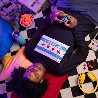Young person on checkered mat wearing Chicago Gadsden Flag Shirt, showcasing a bold protest message, surrounded by retro gaming devices, dice, and snacks, embodying a relaxed, defiant spirit.
