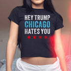 Chicago Hates Trump Women's Baby Tee features a bold slogan and four stars, worn by a woman indoors, highlighting a statement piece for those voicing opposition and supporting equality.