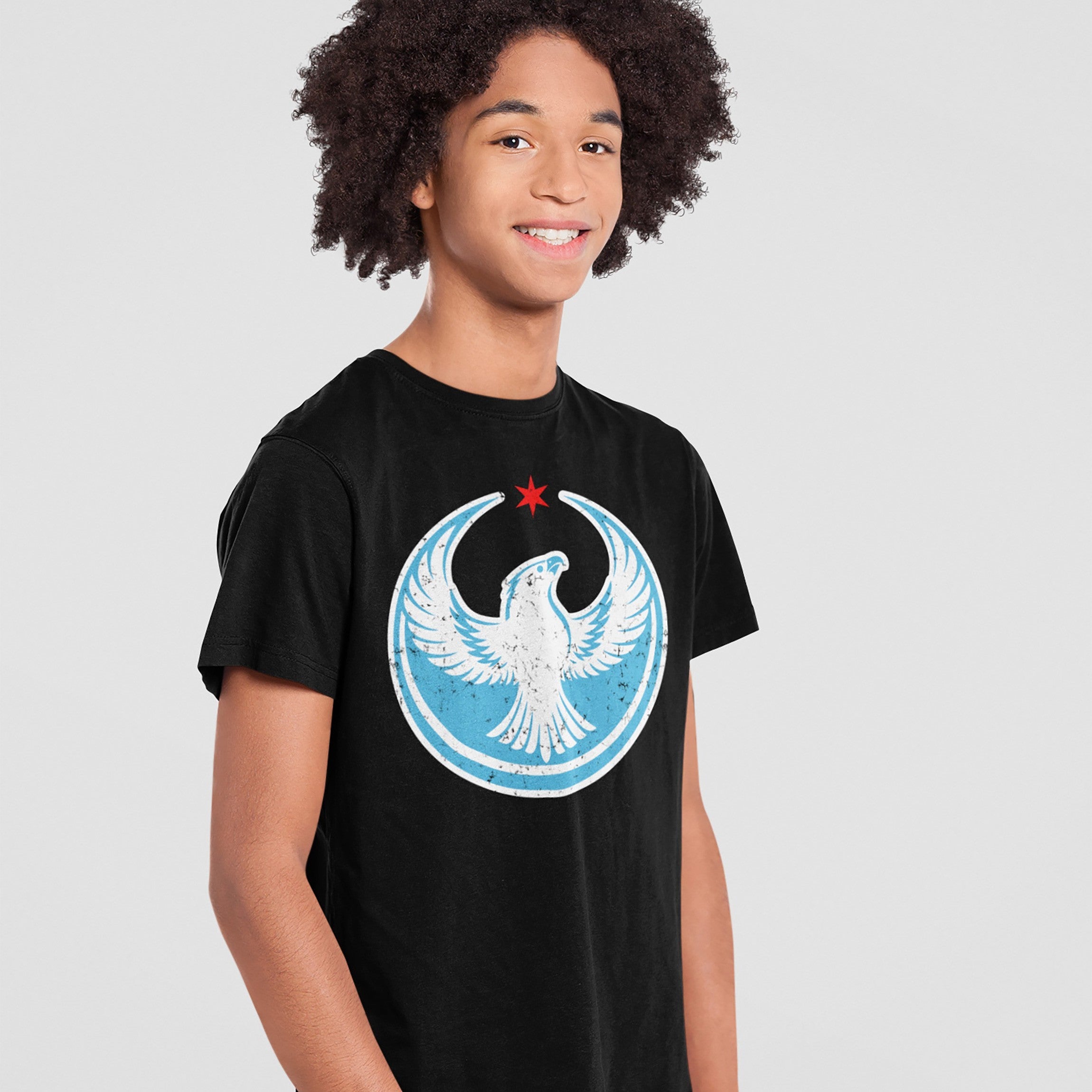 Teenage boy wearing a Chicago Rebel Alliance T-shirt featuring a stylized peregrine falcon and red star emblem, symbolizing anti-fascism and community support, against a light-gray background.