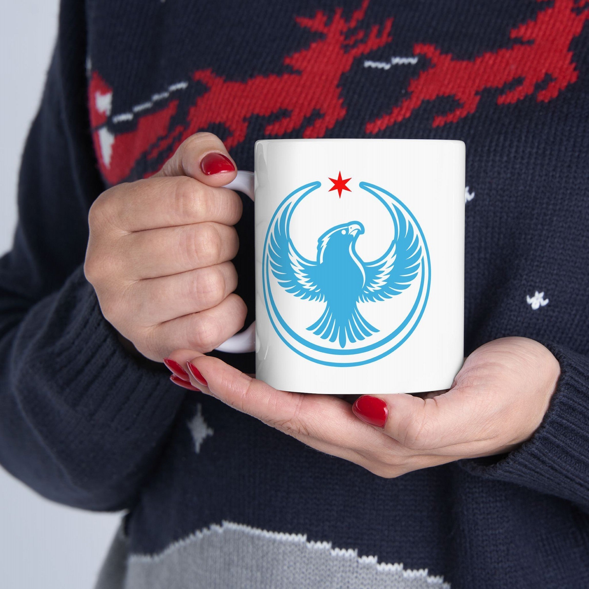 Chicago Rebel Alliance Mug with a blue peregrine falcon emblem and red Chicago star, held by red-nailed hands in a dark sweater, symbolizing resistance and community pride.